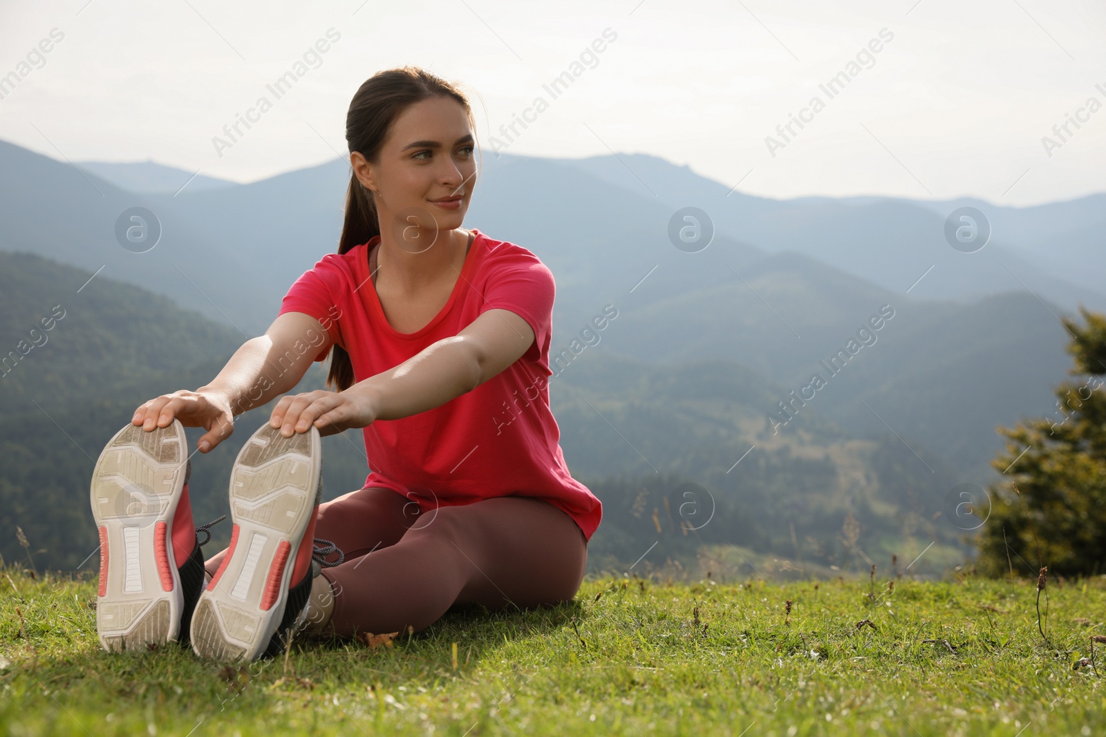 Photo of Young woman doing morning exercise in mountains, space for text