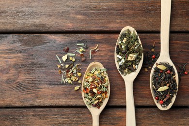 Photo of Spoons with dried herbal tea leaves on wooden table, flat lay. Space for text