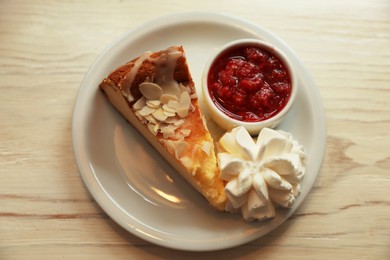 Piece of delicious cake with whipped cream and jam on white wooden table, top view