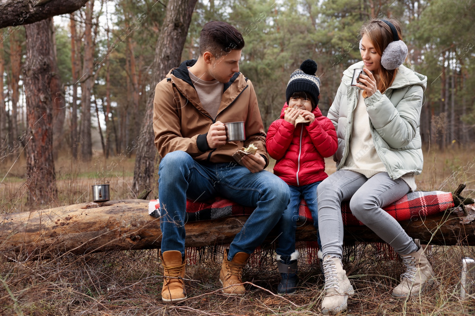 Photo of Happy family with sandwiches and hot drinks in forest