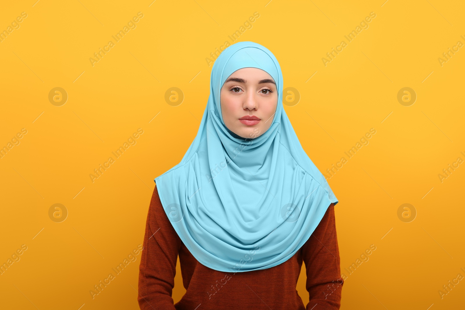 Photo of Portrait of Muslim woman in hijab on orange background