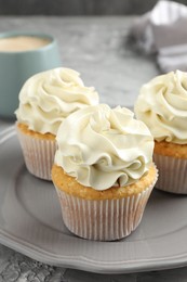 Tasty cupcakes with vanilla cream on grey table, closeup