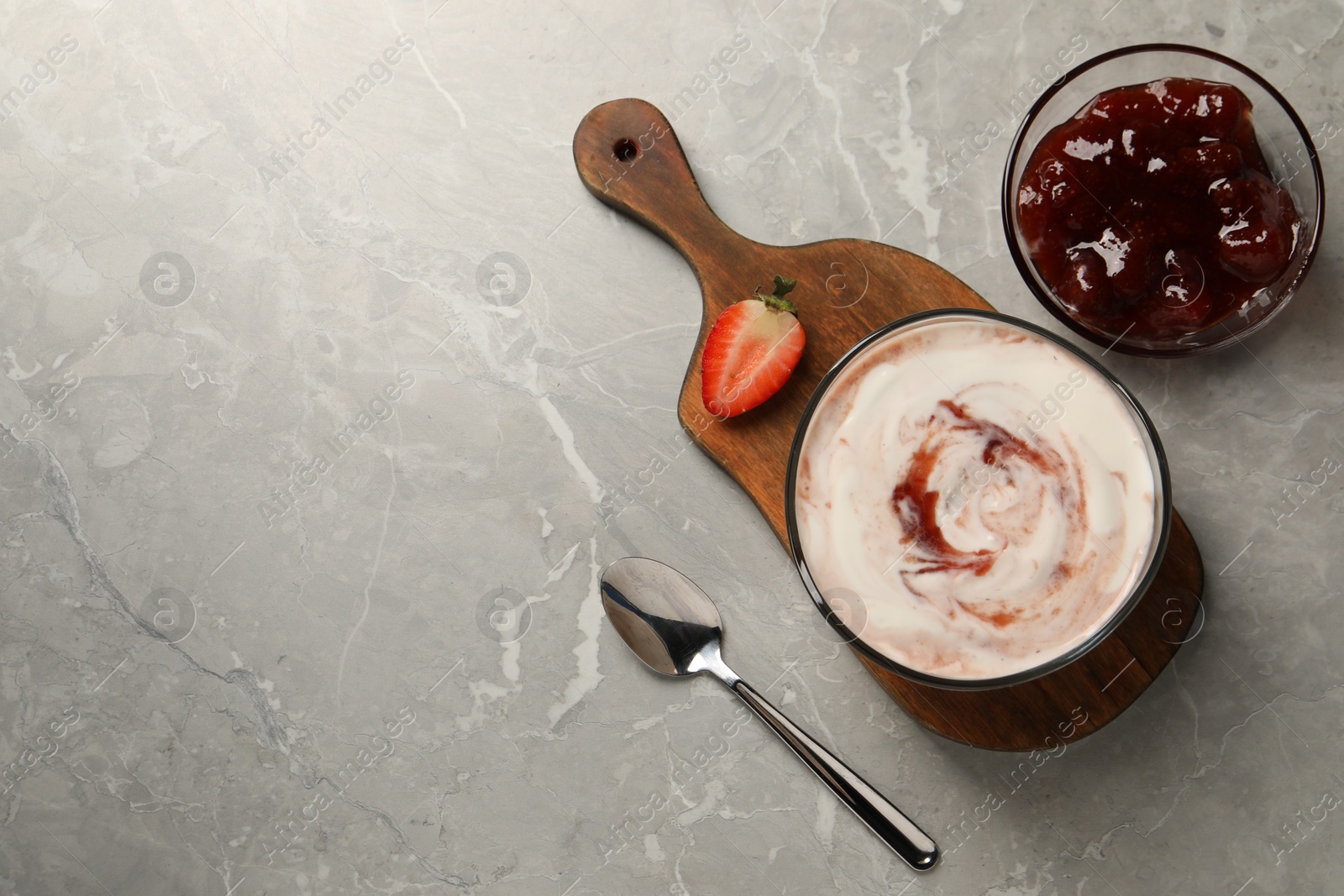 Photo of Tasty yoghurt with jam and strawberry on grey table, flat lay. Space for text