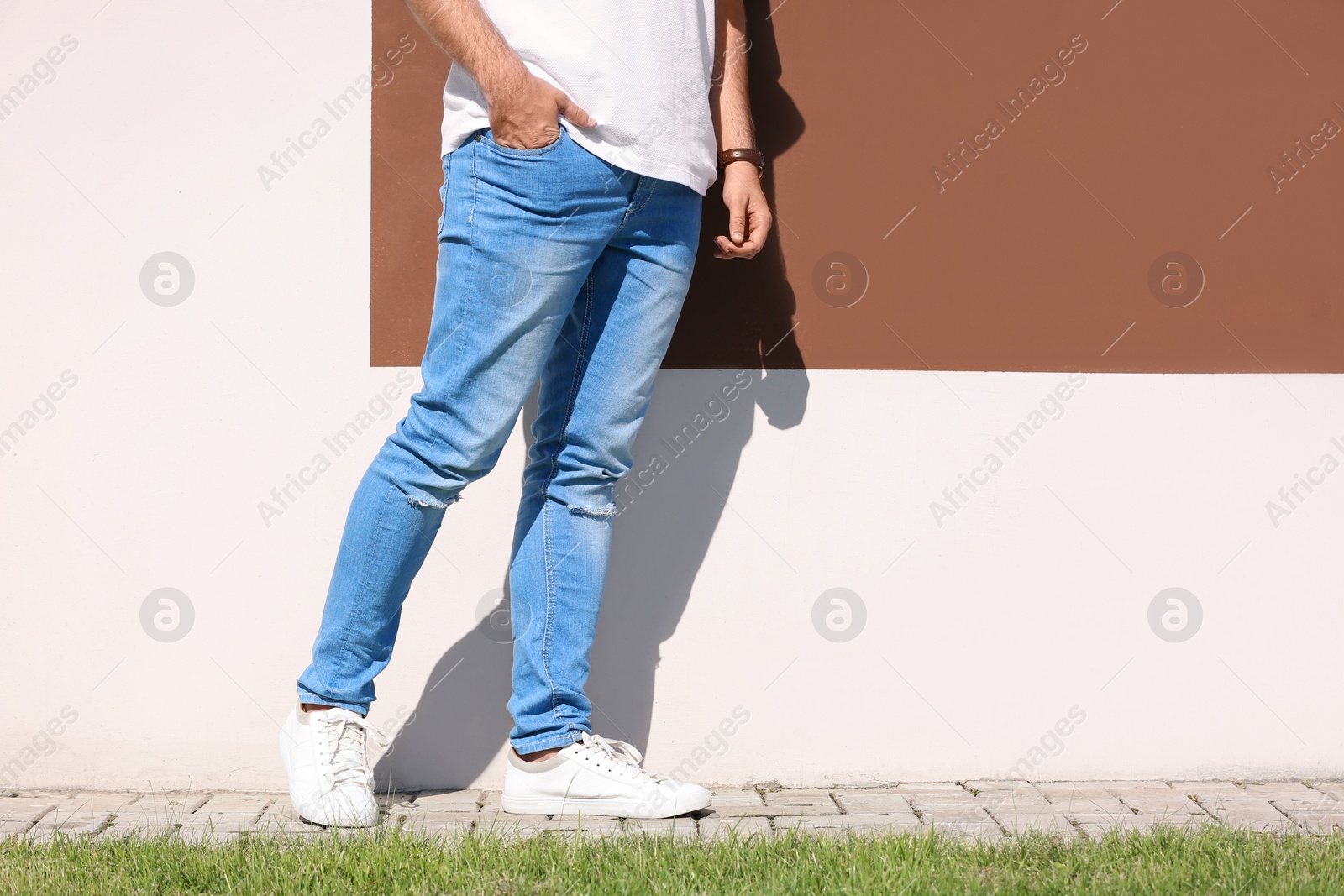 Photo of Young hipster man in stylish jeans posing near color wall