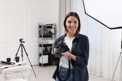 Photo of Young professional photographer with camera in photo studio, space for text