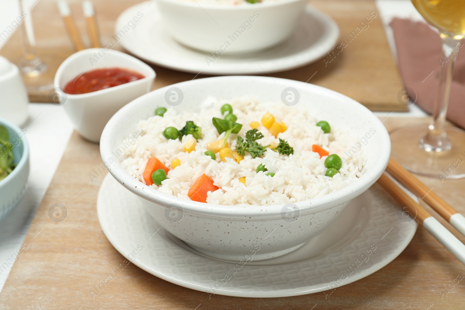 Photo of Bowl of boiled rice with vegetables on table