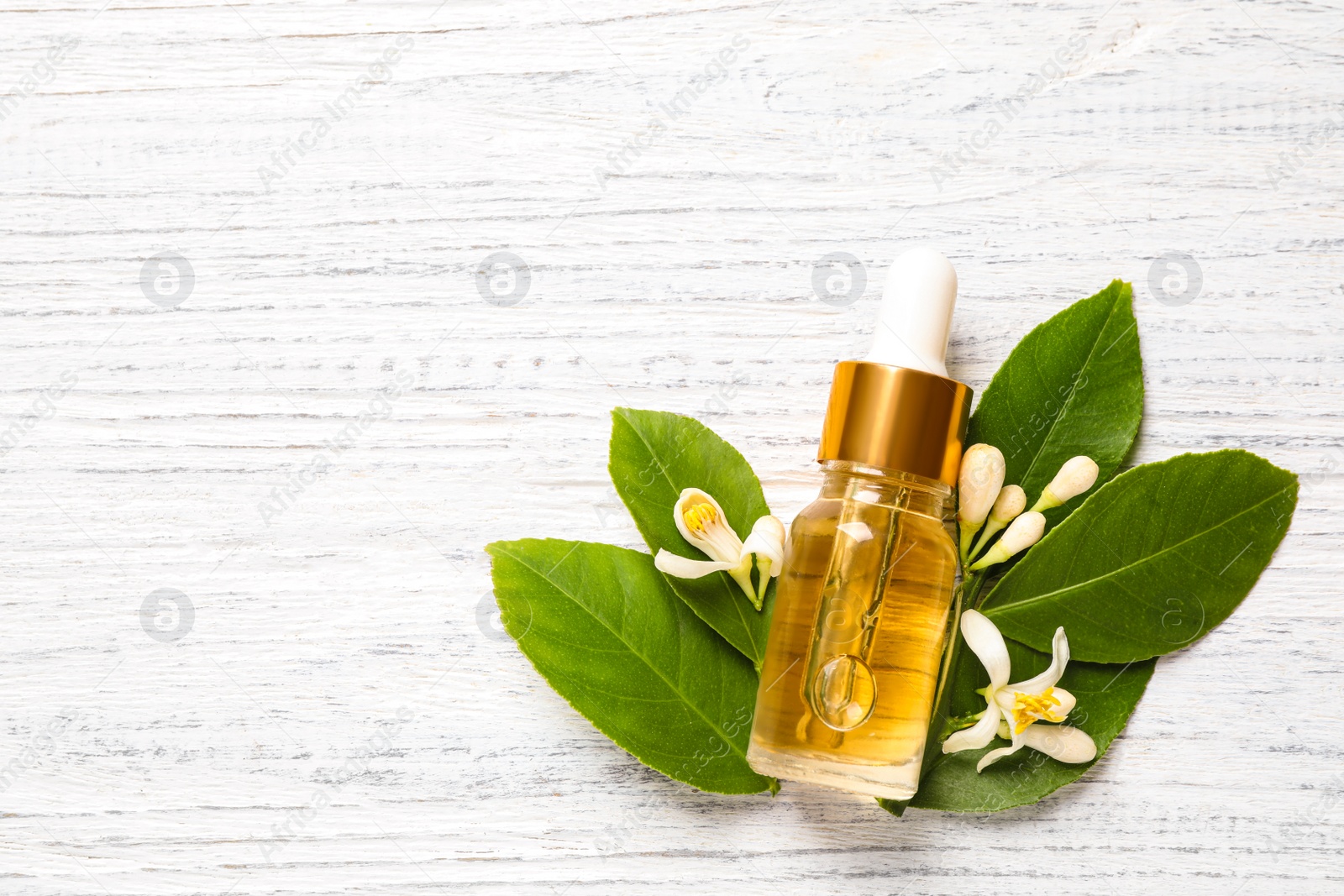 Photo of Flat lay composition with bottle of citrus essential oil on white wooden background. Space for text