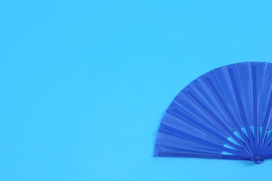Hand fan on light blue background, top view. Space for text