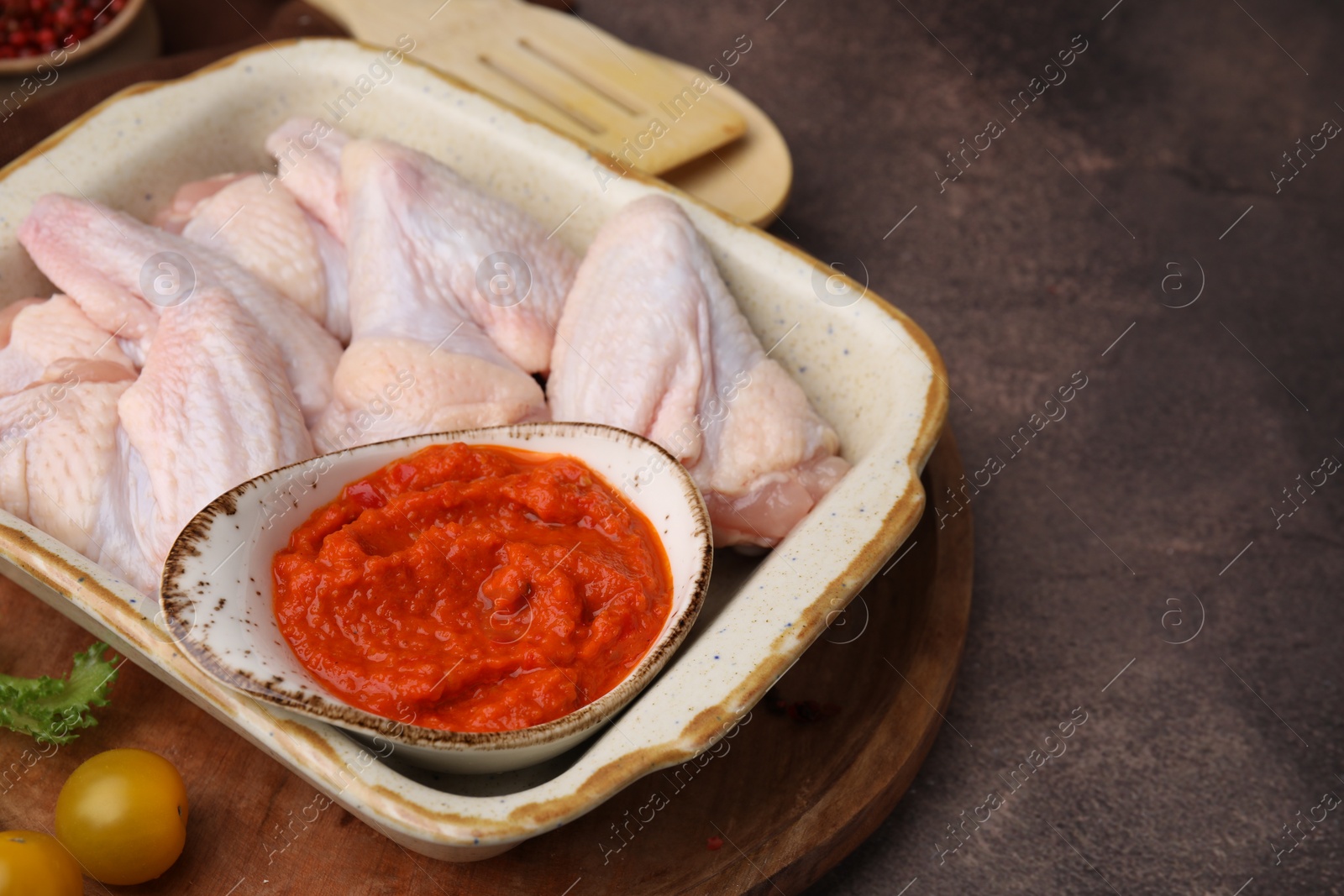 Photo of Fresh marinade and raw chicken on brown textured table, closeup. Space for text