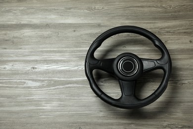 Photo of New black steering wheel on grey wooden table, top view. Space for text
