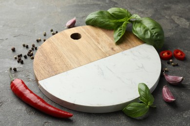 Photo of Cutting board, basil, pepper, chili peppers and garlic on grey table. Space for text