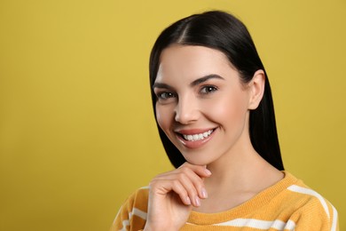 Photo of Portrait of happy young woman with beautiful black hair and charming smile on yellow background