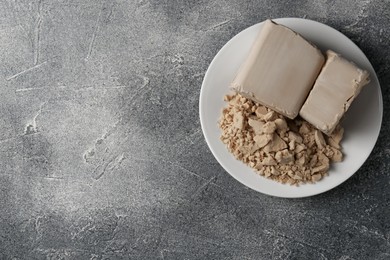 Photo of Compressed yeast on grey table, top view. Space for text