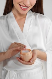 Photo of Happy woman taking hand cream from jar, closeup