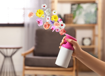 Image of Woman spraying air freshener at home, closeup. Flowered aroma