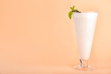 Photo of Glass with vanilla milk shake on color background