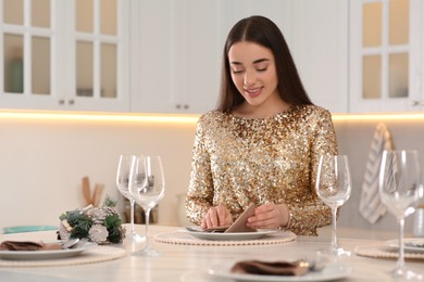 Photo of Happy woman serving table for Christmas in kitchen