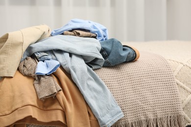 Photo of Pile of different clothes on bed at home