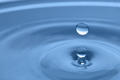 Photo of Splash of clear water with drop on light grey background, closeup. Space for text