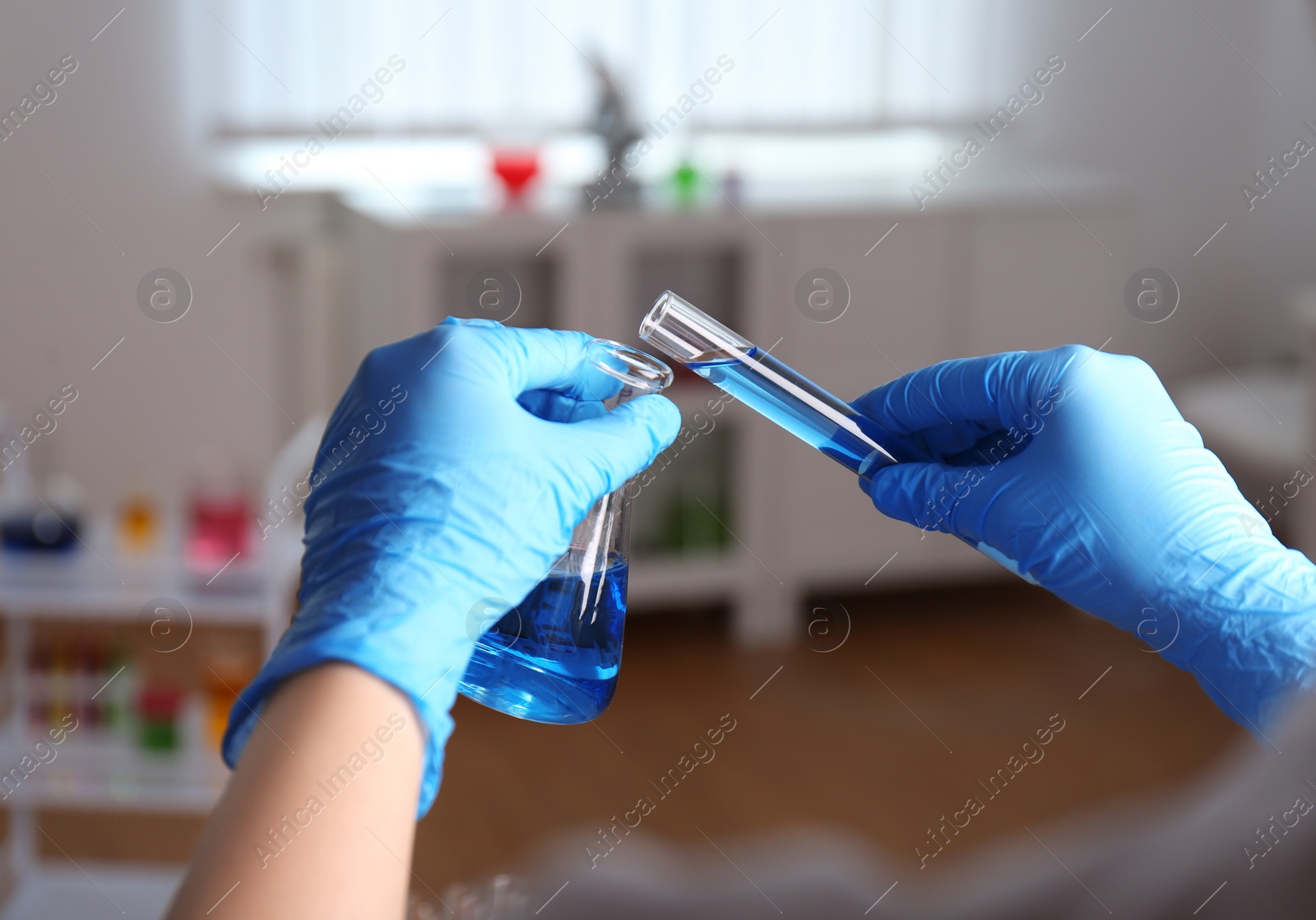 Photo of Scientist holding tube and conical flask at laboratory, closeup. Solution chemistry