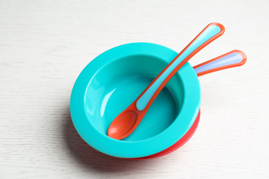 Plastic bowls with spoons on white wooden table. Serving baby food