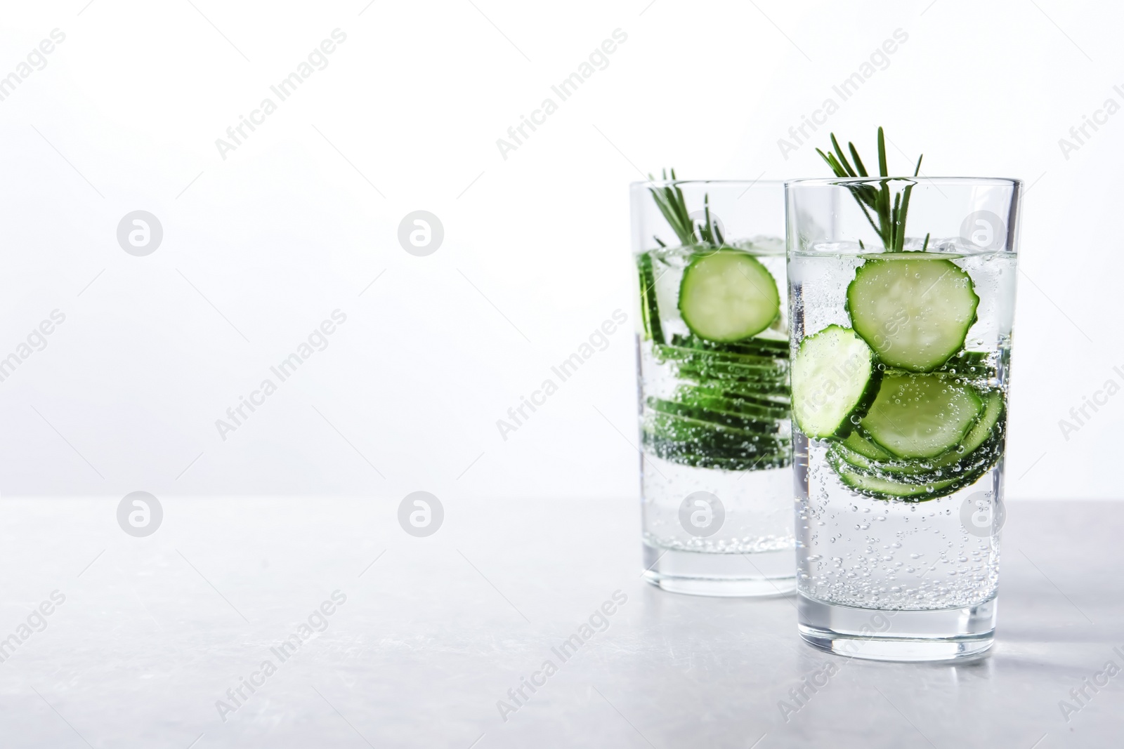 Photo of Glasses of fresh cucumber water on table. Space for text