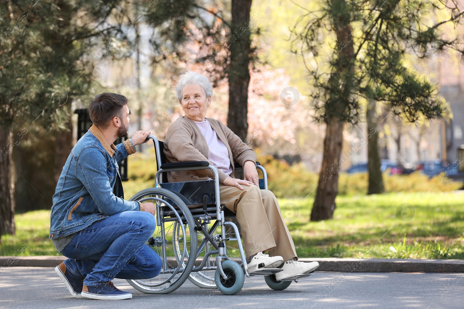 Photo of Senior woman in wheelchair with young man at park