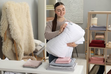Photo of Smiling young woman choosing duvet in home textiles store