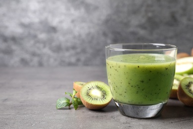 Photo of Delicious kiwi smoothie and fresh fruits on grey table. Space for text