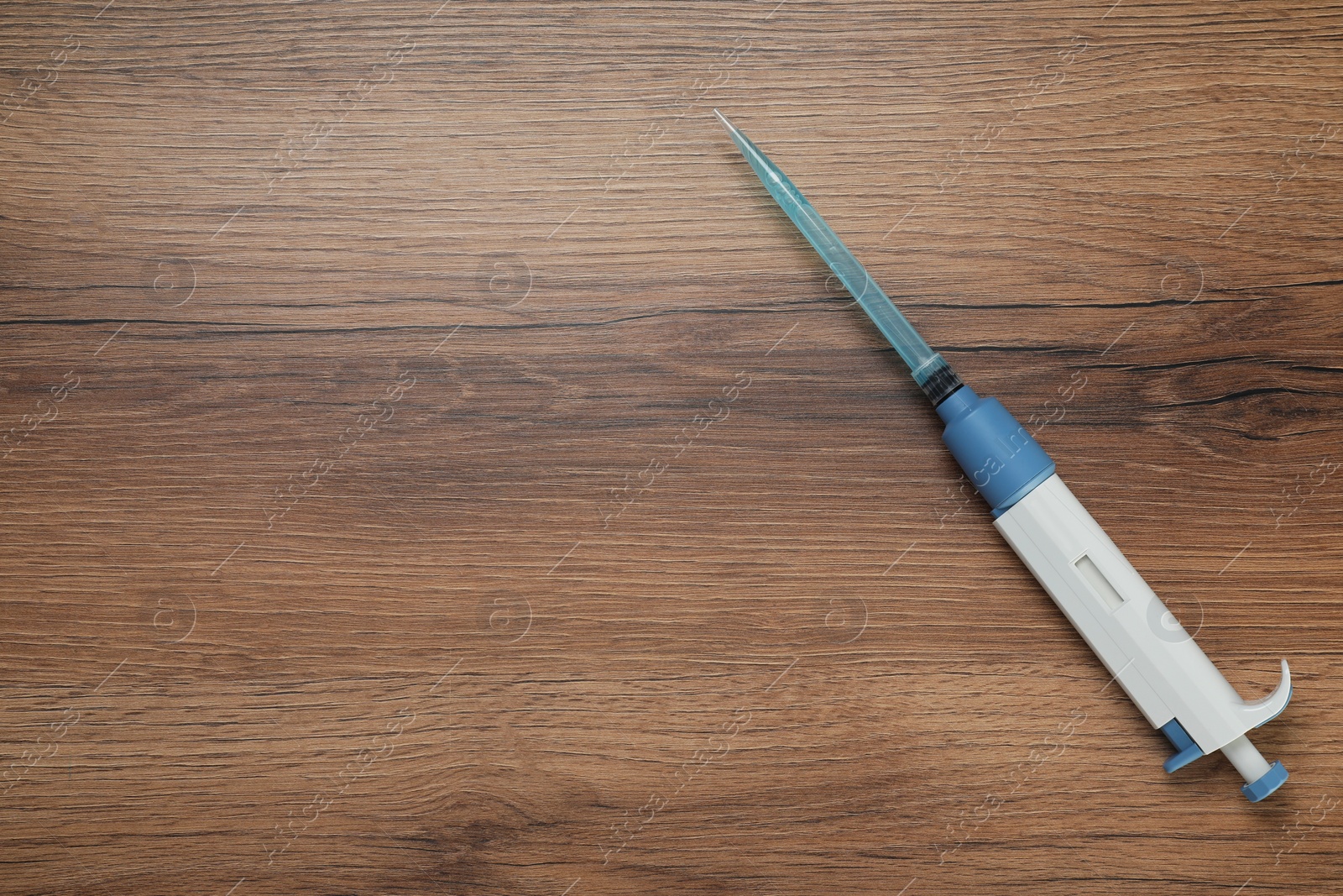 Photo of Laboratory analysis. Micropipette with liquid on wooden table, top view. Space for text