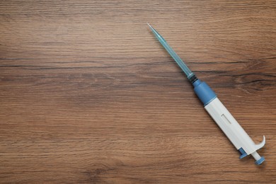 Laboratory analysis. Micropipette with liquid on wooden table, top view. Space for text