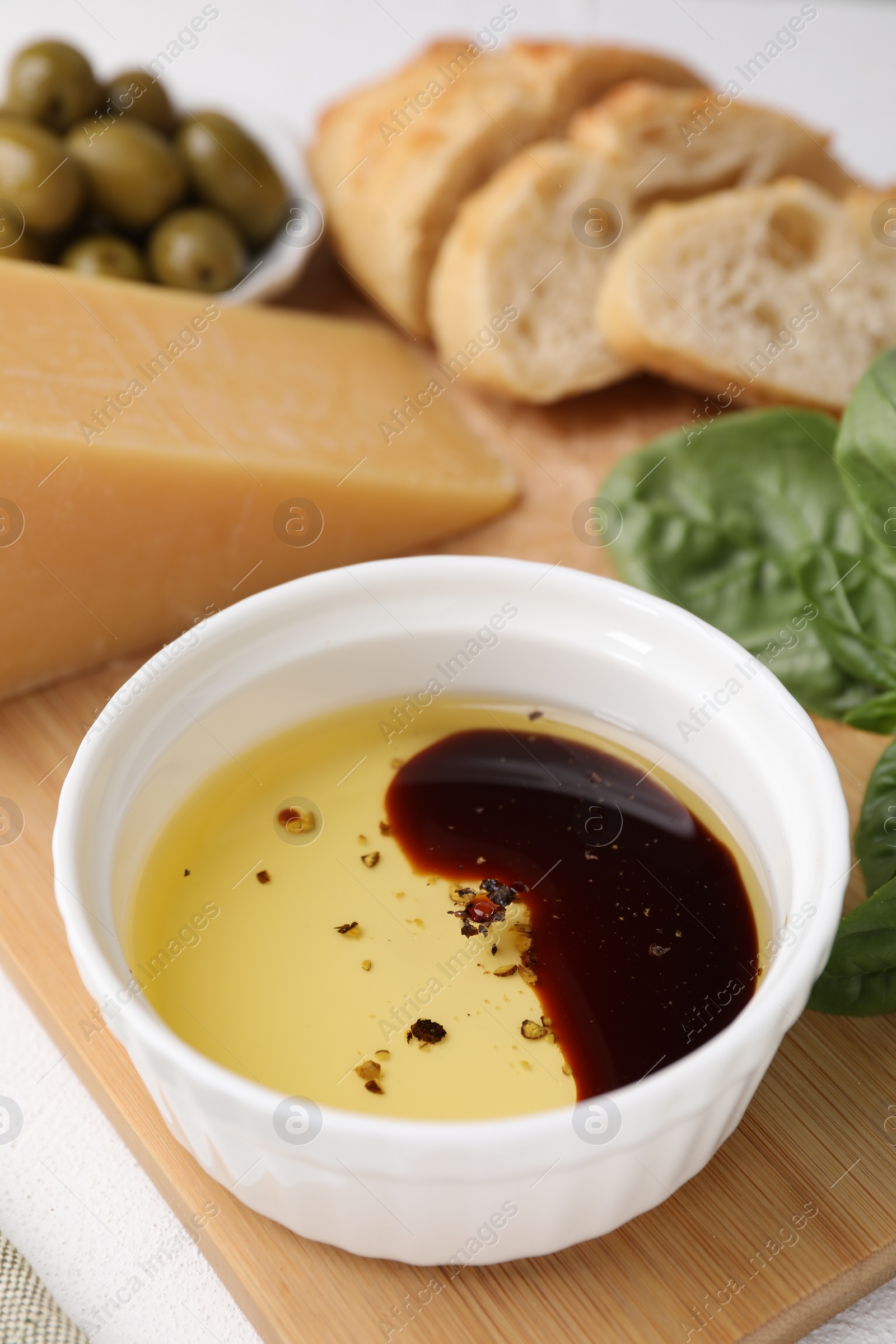 Photo of Bowl of organic balsamic vinegar with oil, basil and other products on table