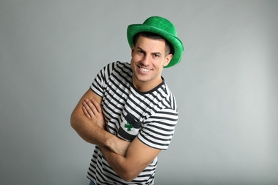 Happy man in St Patrick's Day outfit on light grey background