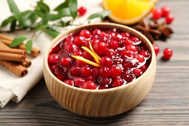 Fresh cranberry sauce with orange peel on wooden table