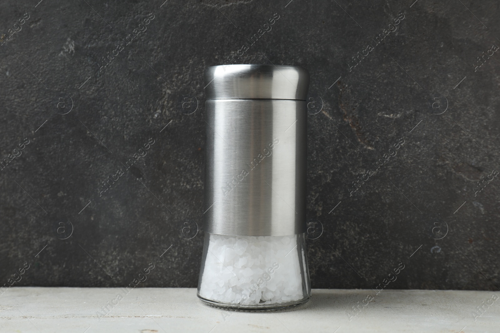 Photo of Salt shaker on light table against grey background, closeup