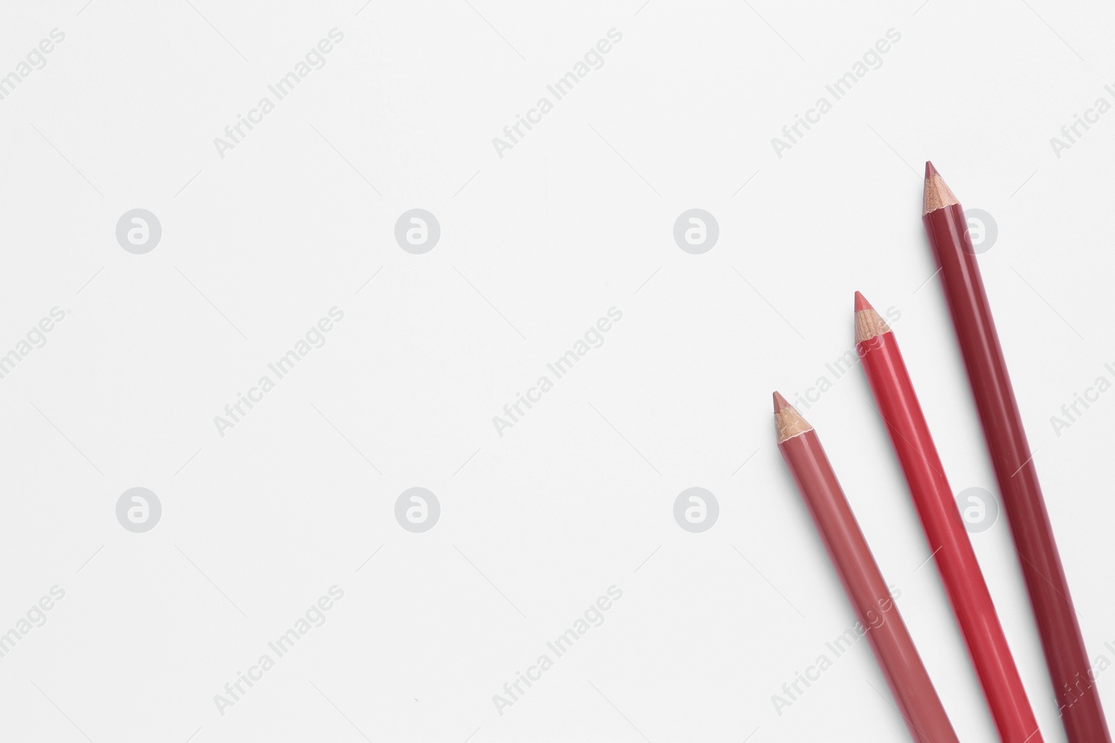 Photo of Different lip pencils on white background, top view. Cosmetic product