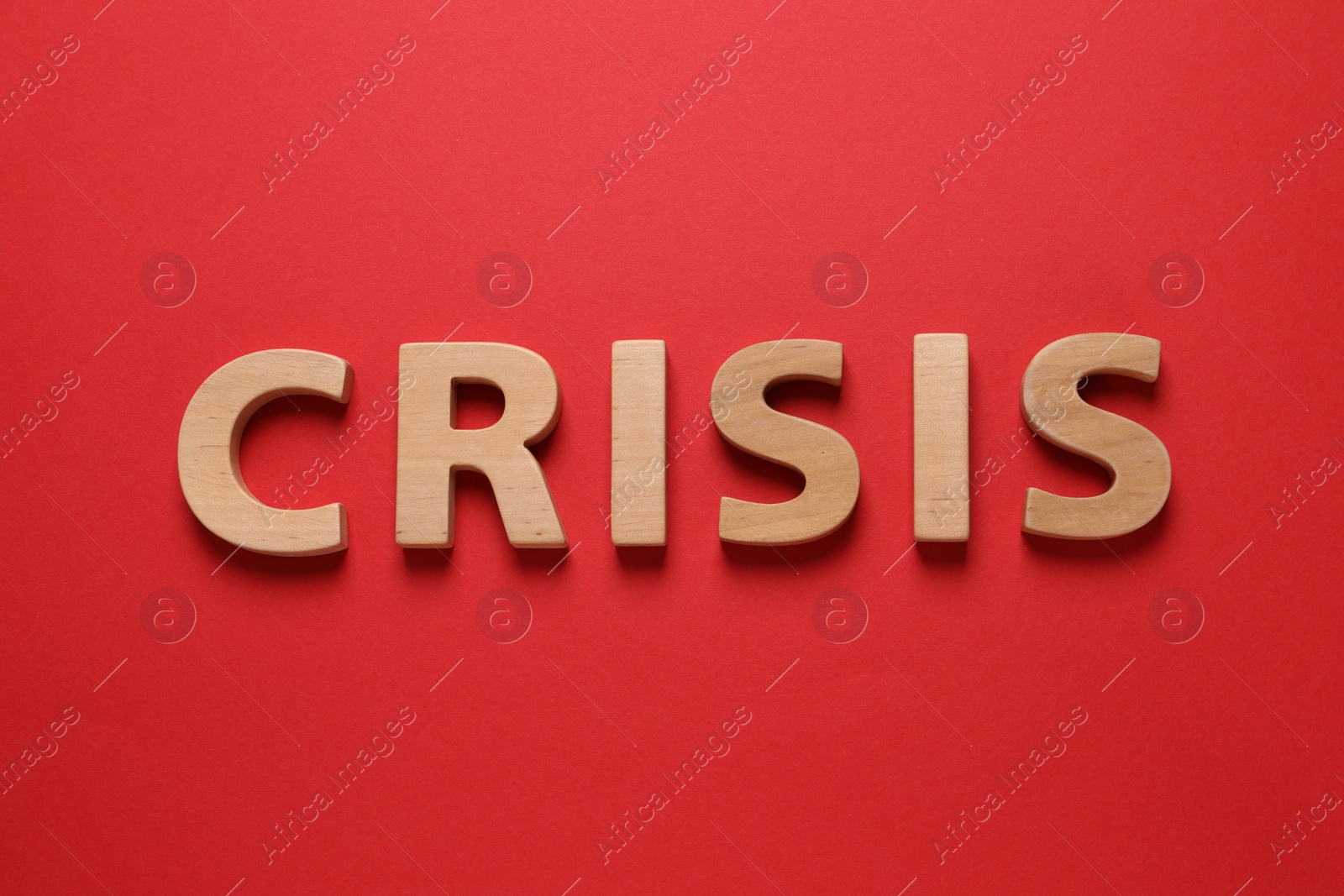 Photo of Word Crisis made of wooden letters on red background, flat lay