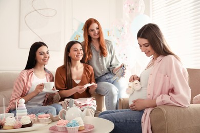 Happy pregnant woman spending time with friends at baby shower party