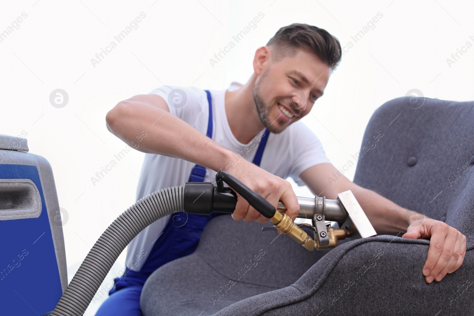 Photo of Dry cleaning worker removing dirt from armchair indoors