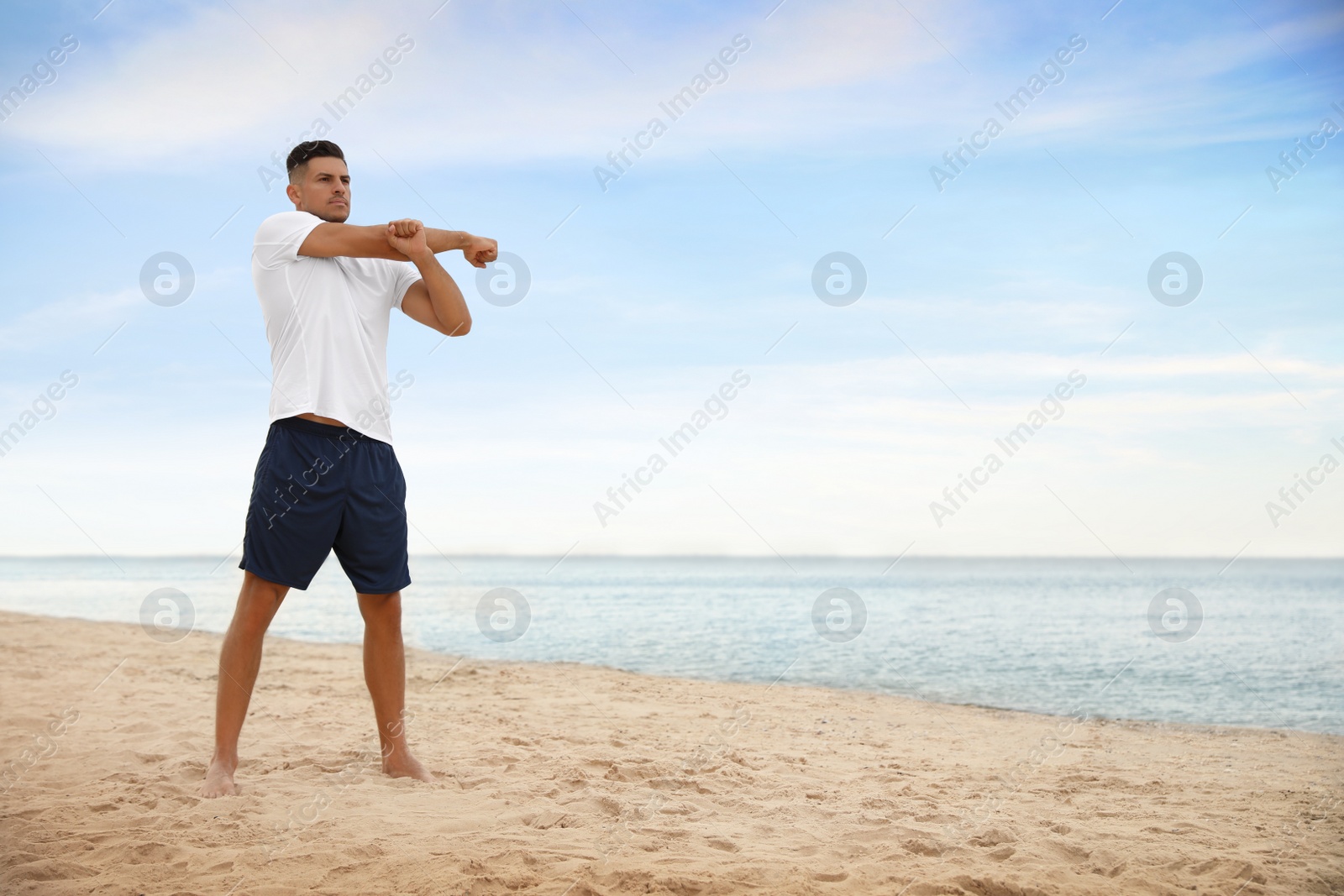 Photo of Muscular man doing exercise on beach, space for text. Body training