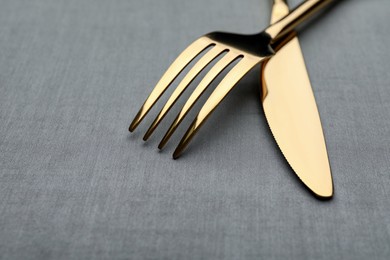 Photo of Golden fork and knife on grey table, closeup