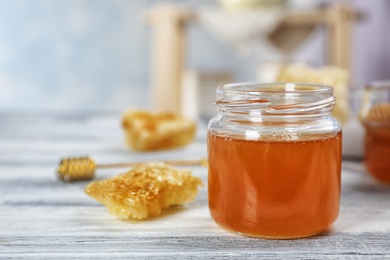 Photo of Jar of honey and honeycombs on table