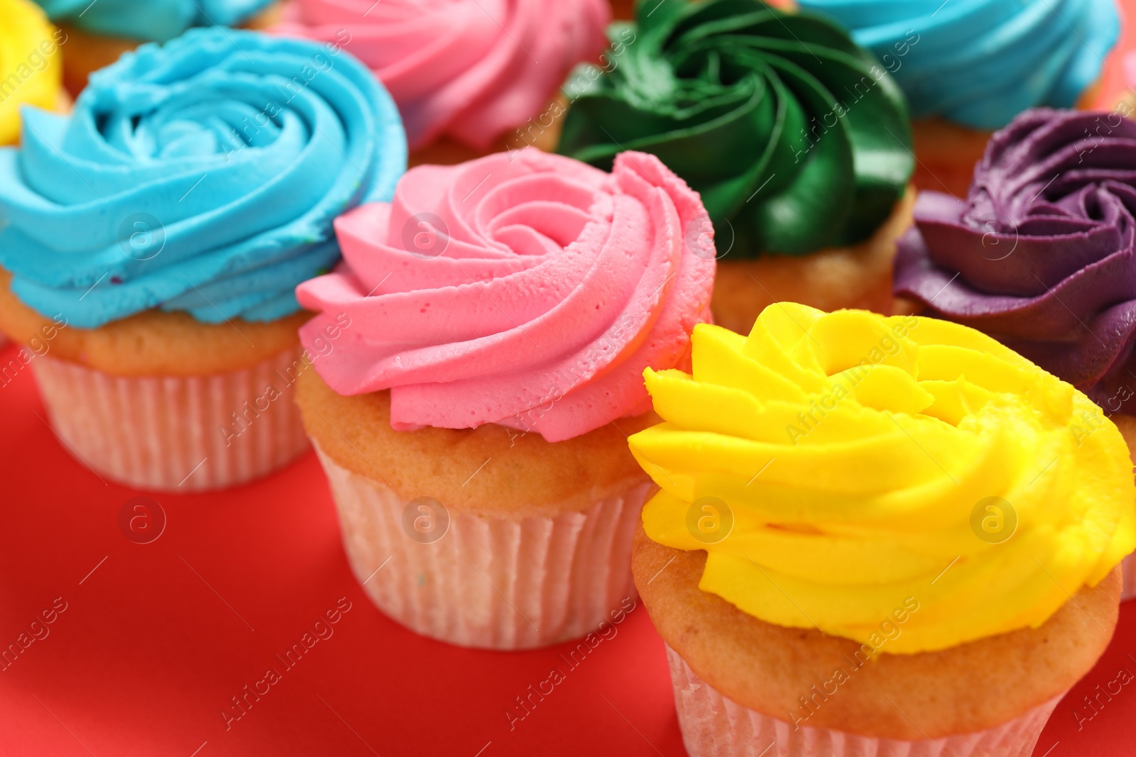 Photo of Delicious cupcakes with bright cream on red background, closeup