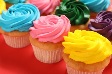 Photo of Delicious cupcakes with bright cream on red background, closeup