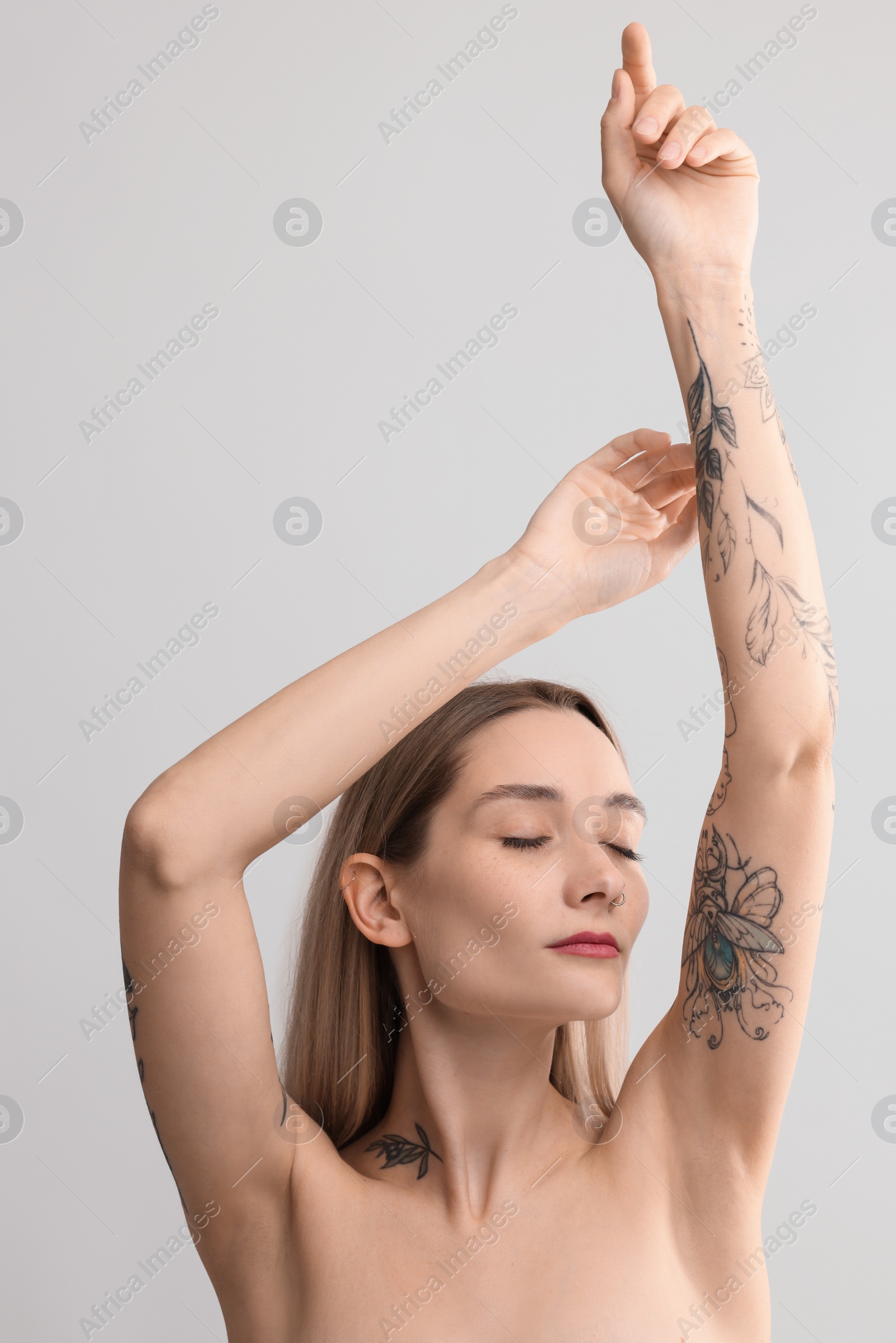 Photo of Portrait of beautiful tattooed woman on light background