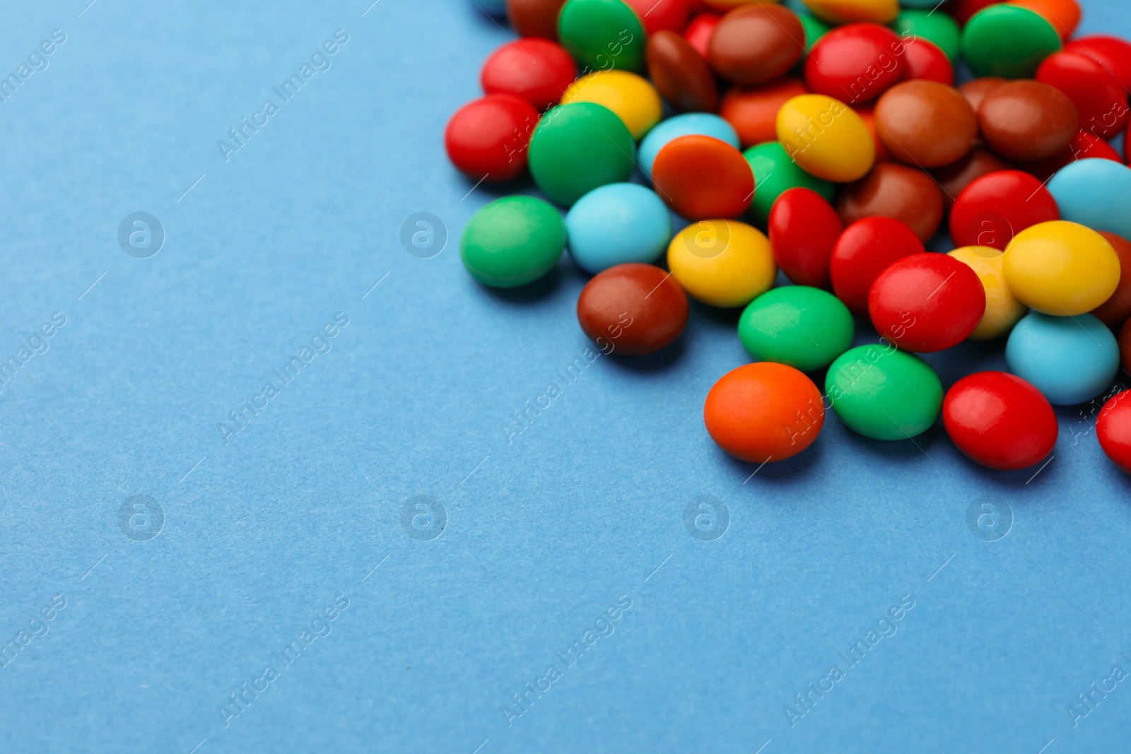 Photo of Tasty colorful candies on blue background, space for text