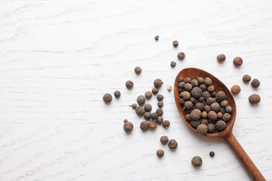 Photo of Peppercorns on white wooden table, flat lay. Space for text