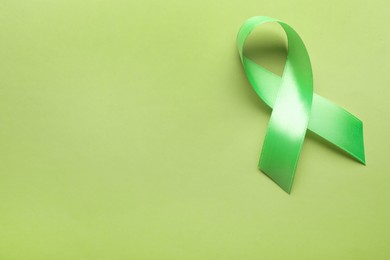 World Mental Health Day. Green ribbon on color background, top view with space for text