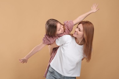 Happy mother with her cute daughter on beige background