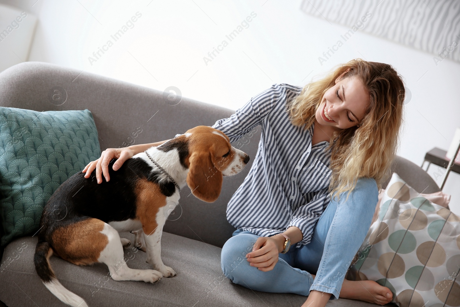 Photo of Young woman with her dog on sofa at home